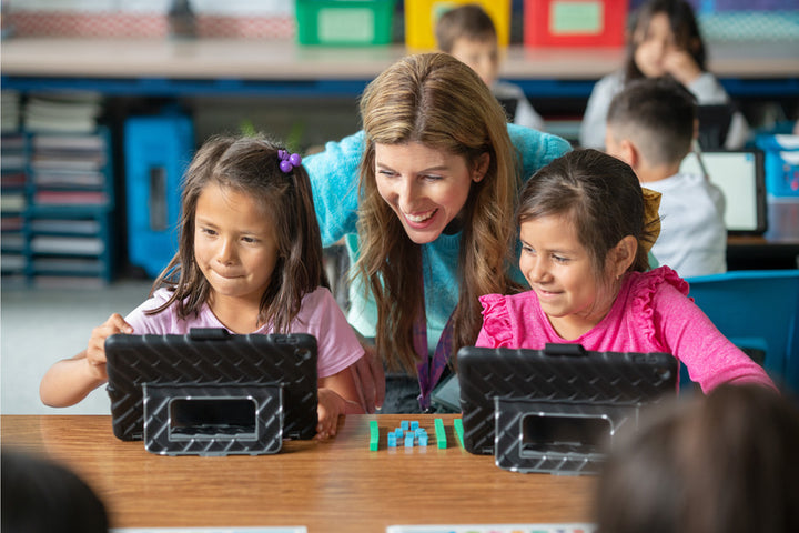a teacher and two students side by side with their ipads in a classroom learning