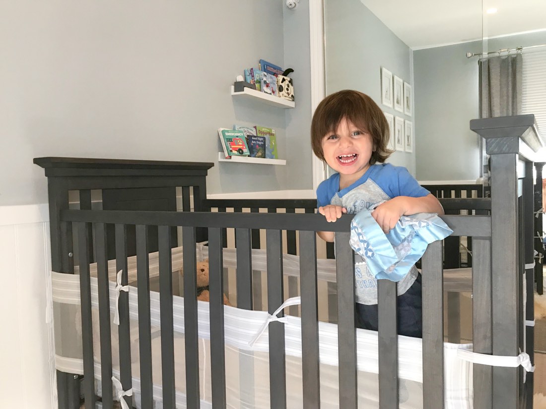 The founder's son standing in his crib