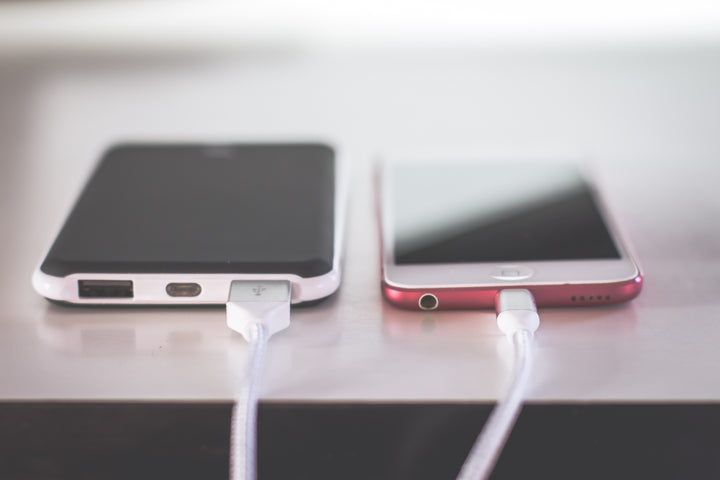 photo of 2 cell phones side by side being charged with cables