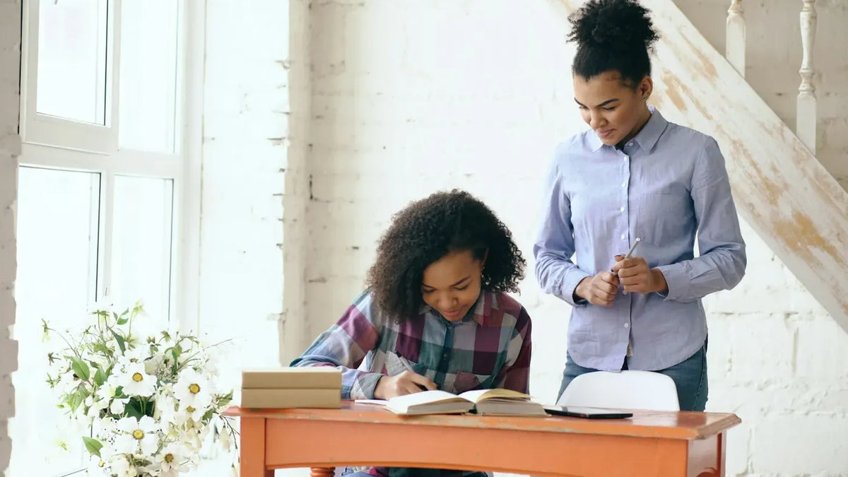 Teenager doing homework at a desk with her mother