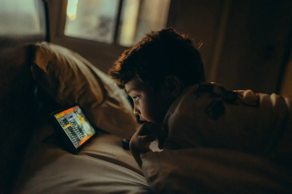 Young boy watching a tablet in bed at night